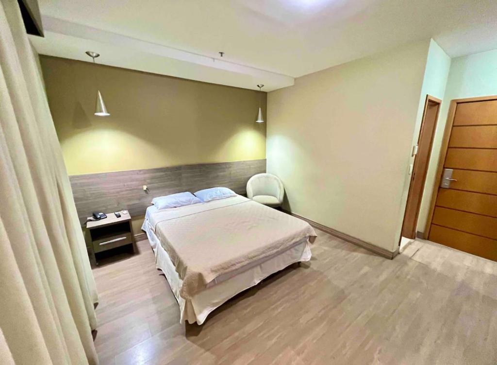 a bedroom with a bed and a chair in a room at Iguassú Suítes - 602 in Nova Iguaçu