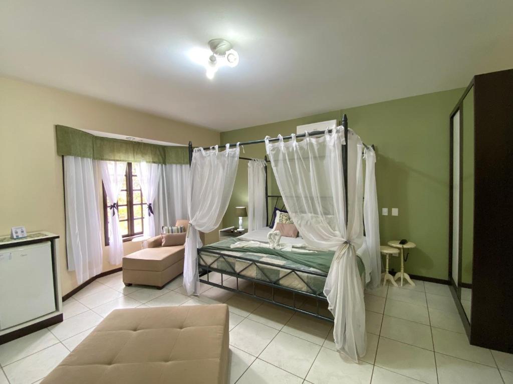 1 dormitorio con cama con dosel y cortinas blancas en Pousada Canasvieiras, en Florianópolis