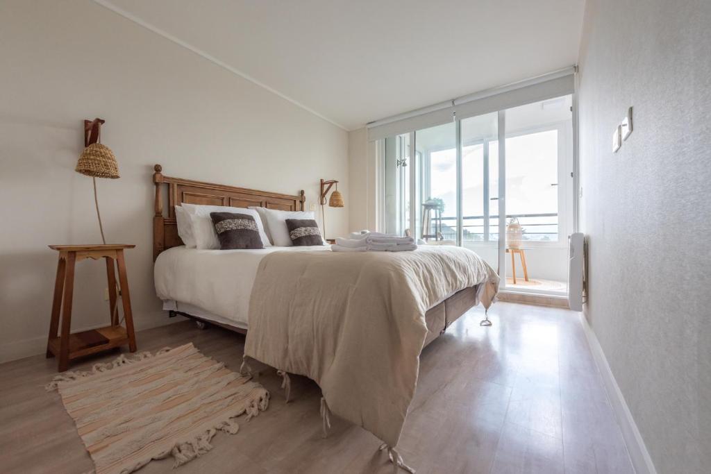 una camera con un grande letto e una grande finestra di Depto con exquisita Vista al Lago y Tinaja a Puerto Varas