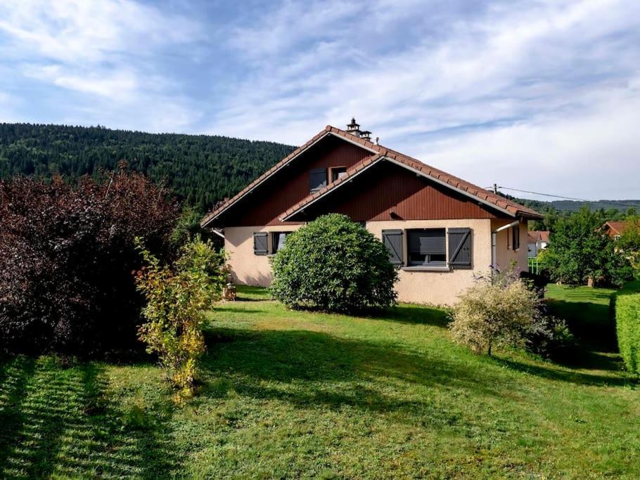 une maison avec une cour herbeuse devant elle dans l'établissement Chalet Marie-Louise - Gérardmer, à Gérardmer