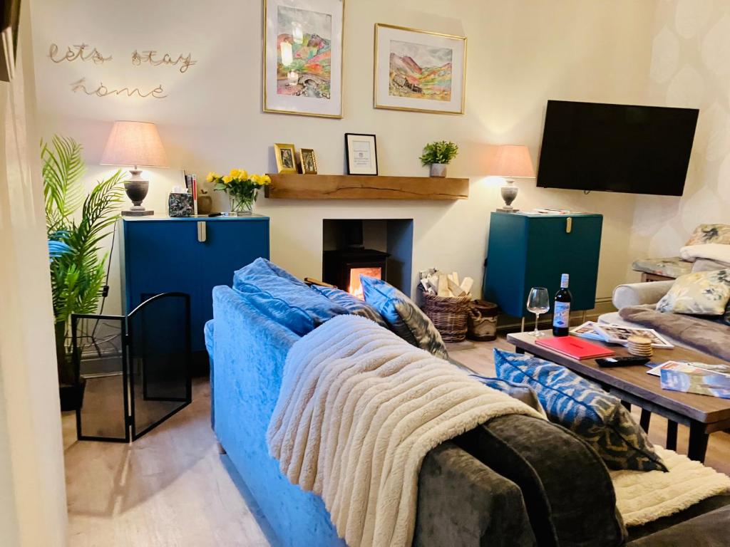 un soggiorno con divano blu e camino di Stunning 3-Bed Cottage Hot Tub Wi-Fi Parking ad Appleby