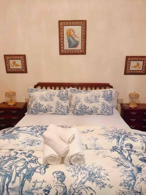 a bed with blue and white sheets and pillows at La Casa de Manolita in Baena