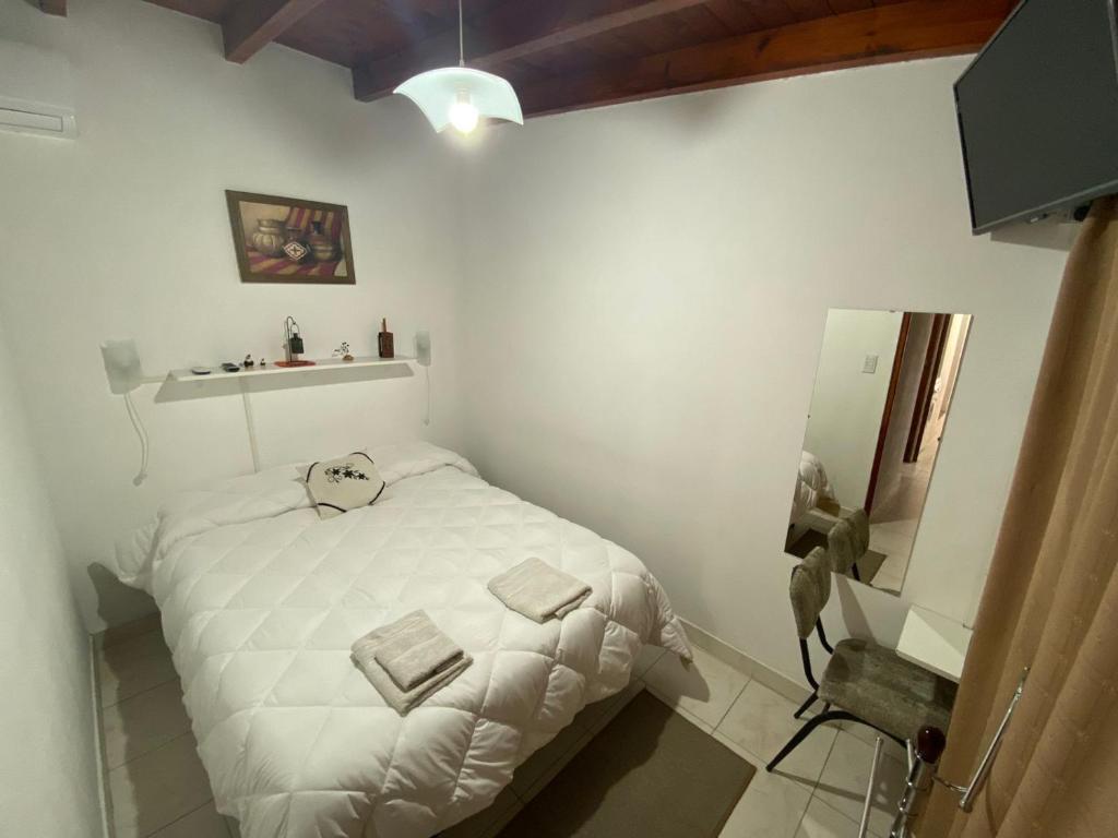 Un pequeño dormitorio con una cama blanca y un lavabo en Like Home en Salta