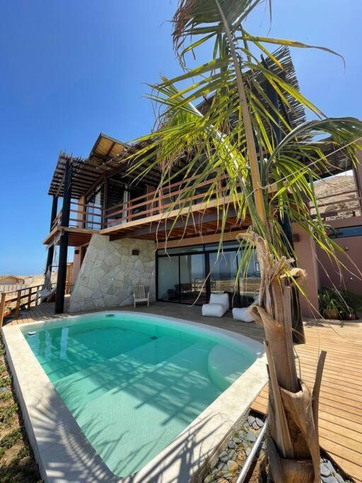 uma casa com piscina em frente a uma casa em Casa Natural em Los Órganos