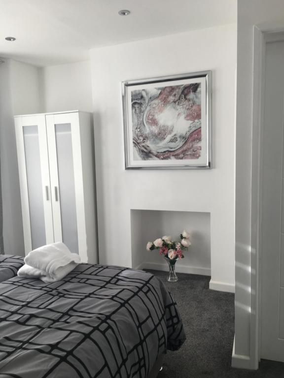 a bedroom with a bed and a painting on the wall at Amber Apartments, FREE PARKING, 3 bedrooms, sleeps 5, 1 en-suite plus 1 bath/shower room in Swindon