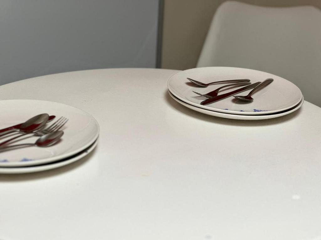 zwei weiße Platten mit Gabeln und Löffeln auf einem Tisch in der Unterkunft Grandma’s House in Walsall