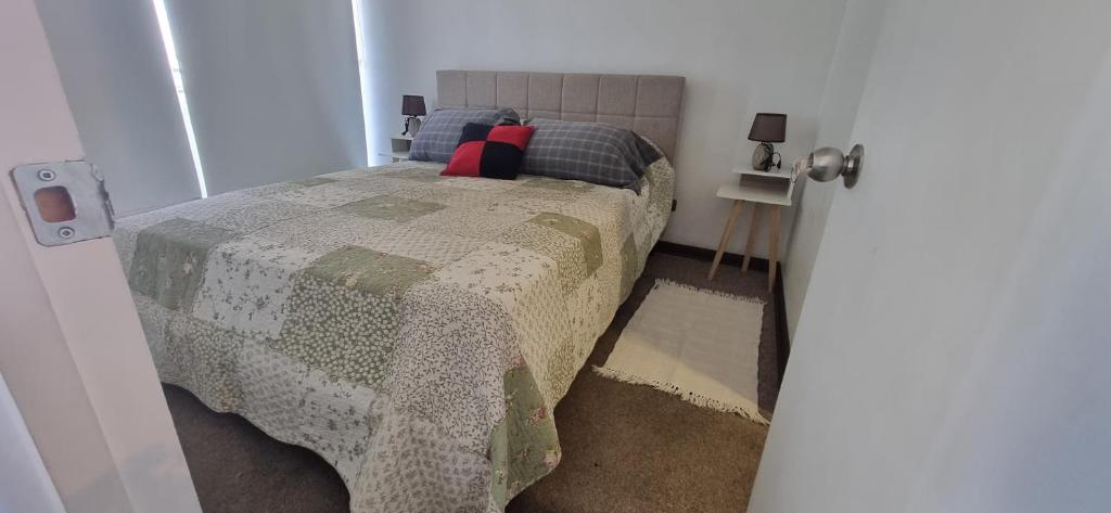 een slaapkamer met een bed met een quilt bij Departamento pasos Mall Plaza Vespucio in Santiago