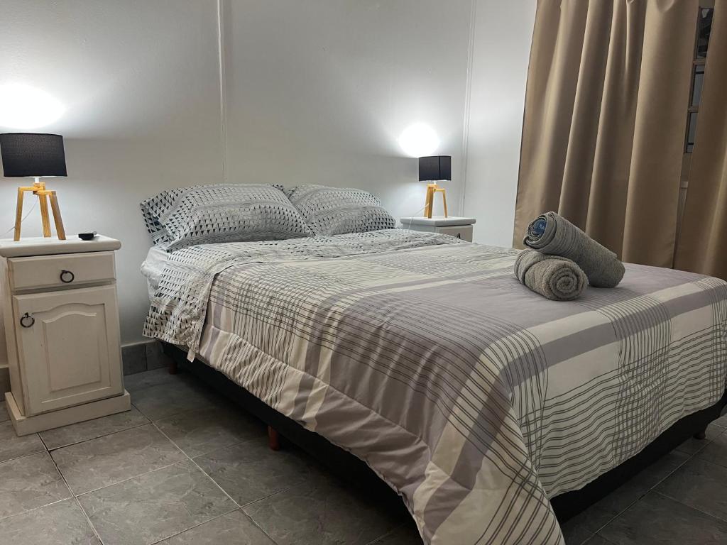 a bed with a striped blanket and two pillows on it at Complejo Lamadrid - semiprivado in Ciudad Lujan de Cuyo