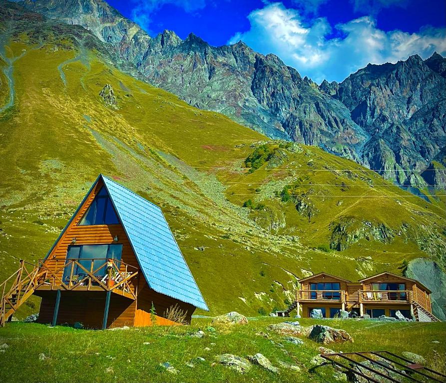 a house with a blue roof on a mountain at Alone Cottage Kazbegi in Stepantsminda