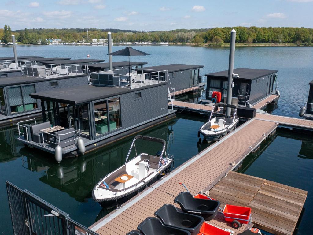 dois barcos estão ancorados numa doca num lago em Luxury houseboat with roof terrace and beautiful view over the Mookerplas em Middelaar