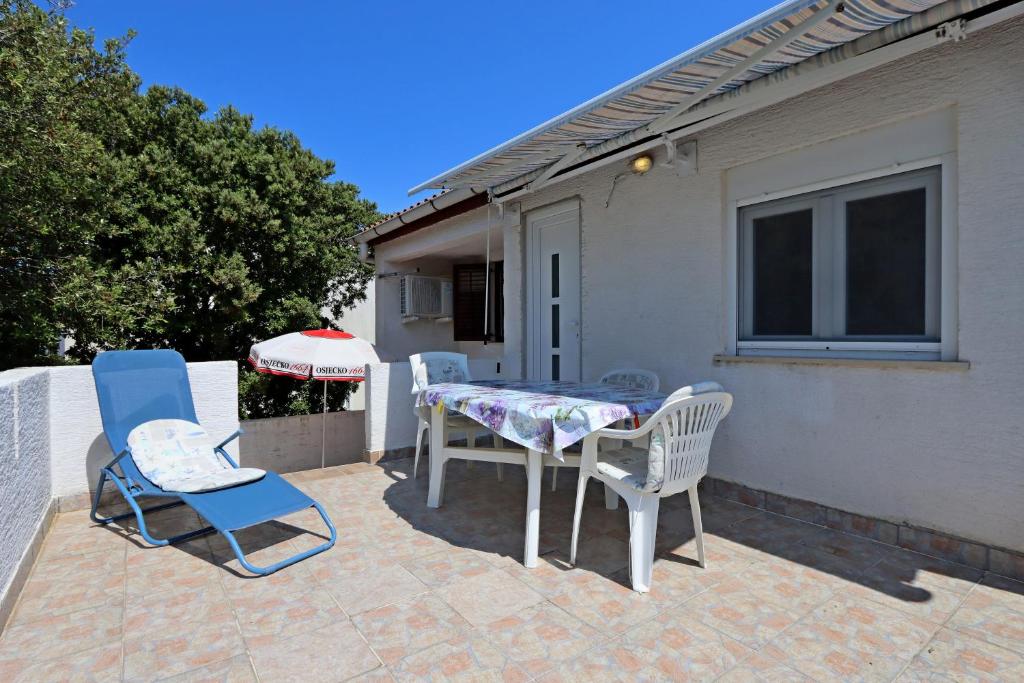 a patio with two chairs and a table and a umbrella at Apartments with parking space Mandre, Pag - 11600 in Kolan