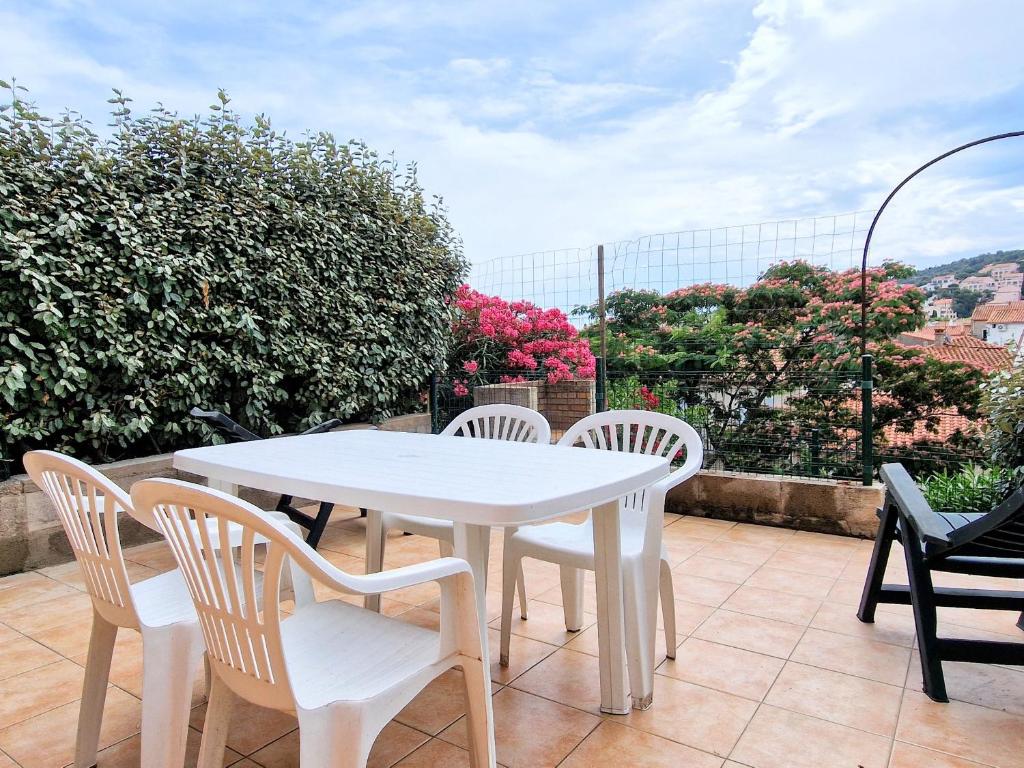 une table blanche et des chaises sur une terrasse dans l'établissement Studio cabine à Banyuls-sur-Mer, terrasse, parking privé, proche centre-ville et plage - FR-1-309-277, à Banyuls-sur-Mer