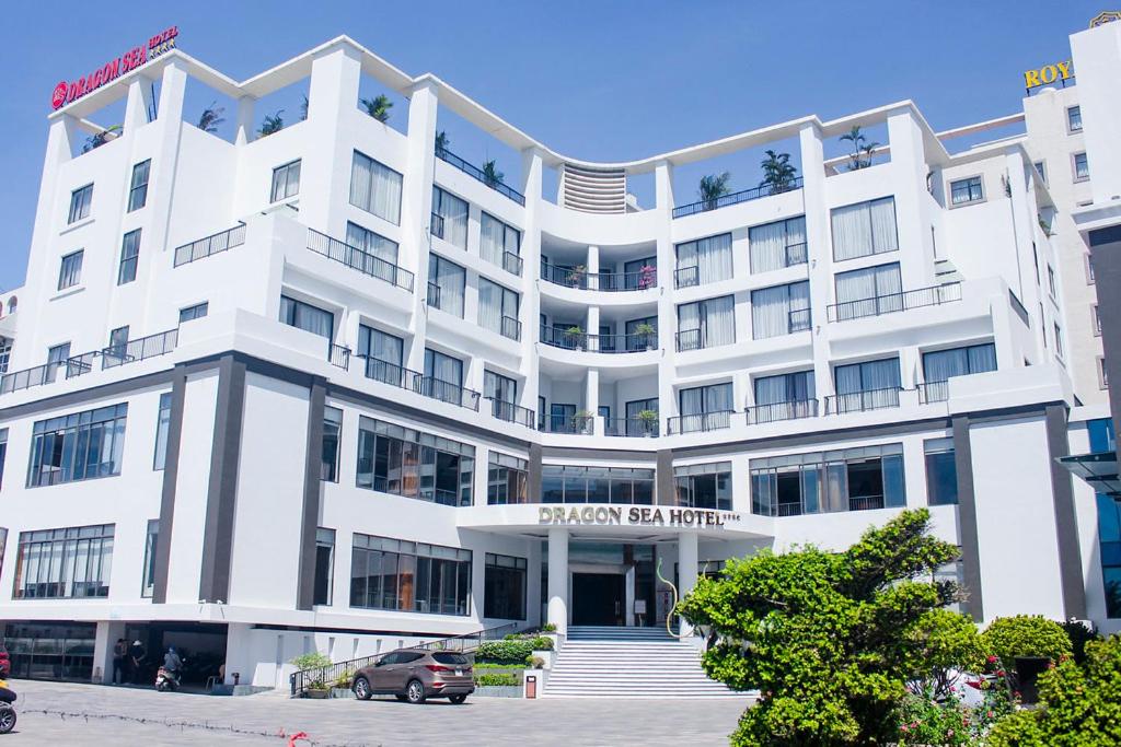 un grand bâtiment blanc avec une voiture garée devant. dans l'établissement Dragon Sea Hotel, à Sầm Sơn