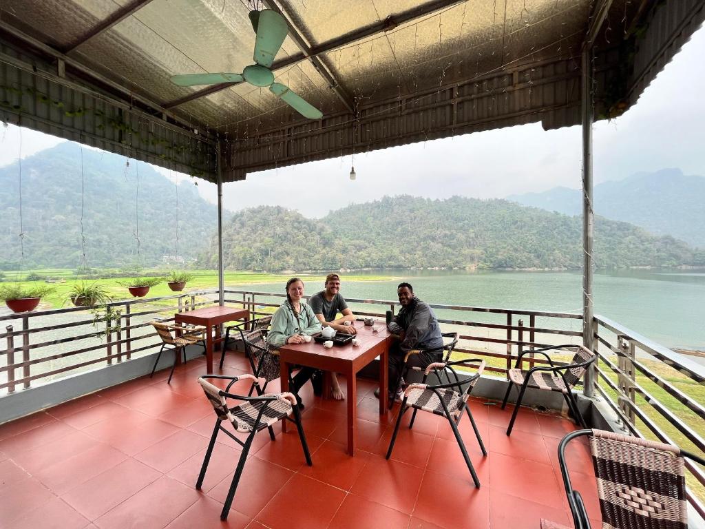 a group of people sitting at a table on a balcony at Nhà Nghỉ Sơn Lâm - Ba Bể lake Best view in Bak Kan