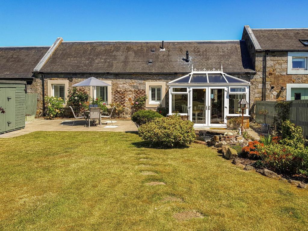 a house with a conservatory in front of a yard at Hilton Farm Steadings in Limekilns