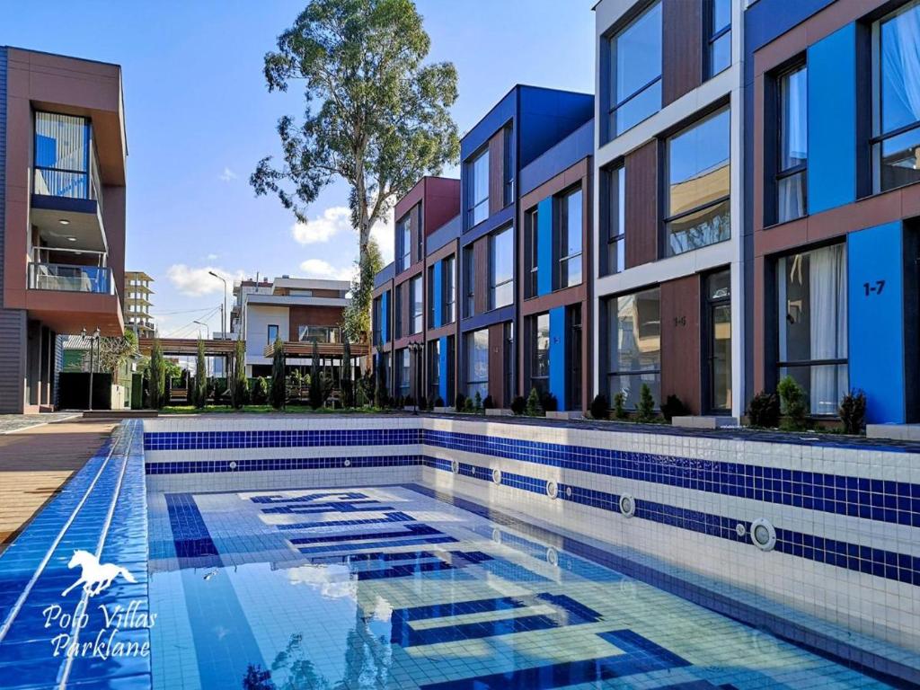 a swimming pool in front of a building at Liana Polo Villas Parklane in Batumi