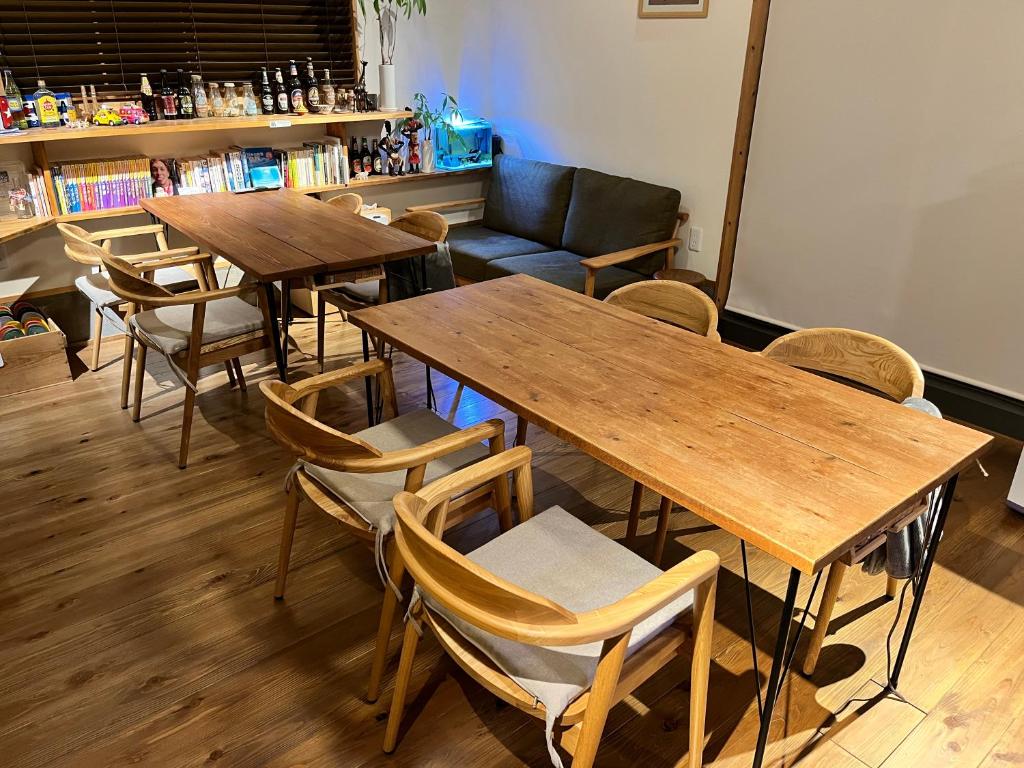 un restaurant avec des tables et des chaises en bois ainsi qu'un canapé dans l'établissement Goto Backpackers Pole, à Shinkamigoto