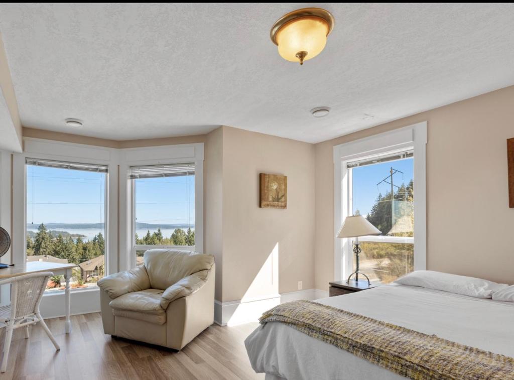 1 dormitorio con 1 cama, 1 silla y ventanas en Executive pet friendly lower suite with ocean view en Ladysmith