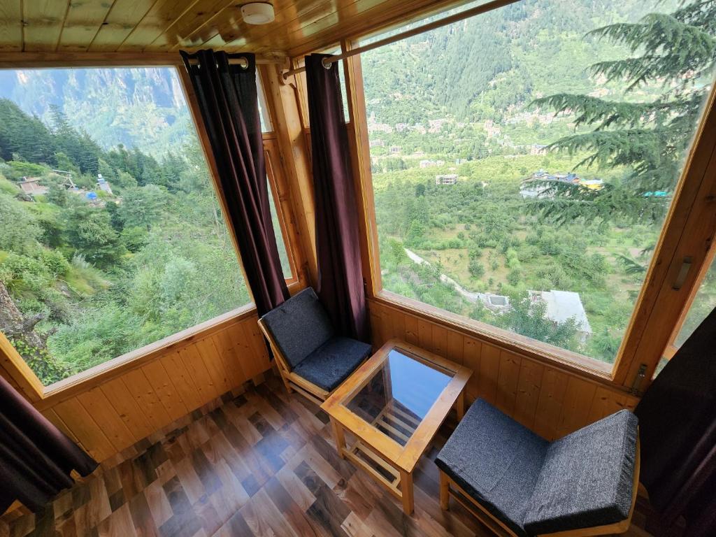 two chairs in a room with a large window at Timberwolves in Manāli