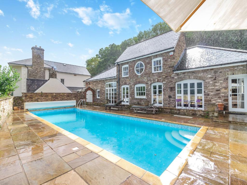 a large swimming pool in front of a brick house at The Coach House - Uk45027 in Gilwern