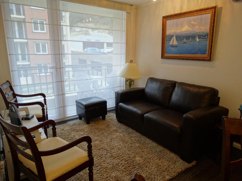 uma sala de estar com um sofá de couro e uma janela em Apart & Tour em Puerto Varas