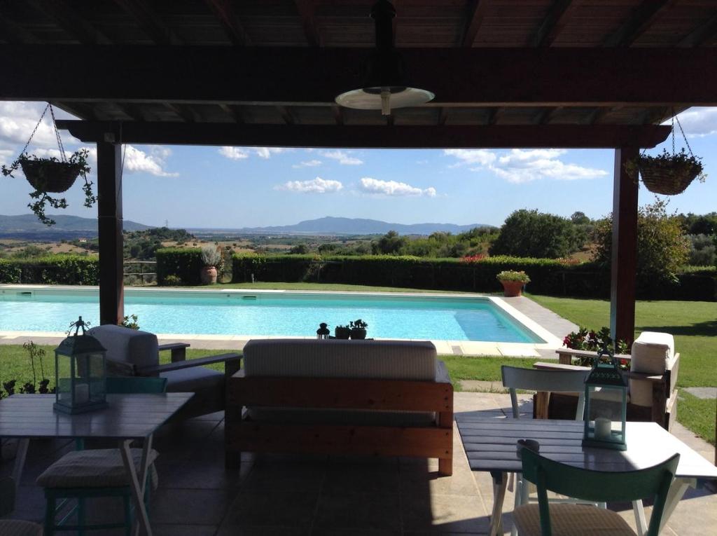 eine Terrasse mit einem Pool mit Tischen und Stühlen in der Unterkunft Agriturismo Prati degli Orti in Montiano