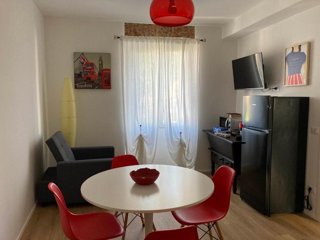 una pequeña sala de estar con una mesa blanca y sillas rojas en Casa Nova Luxury Apartment Suite Limoni, en Nova Milanese