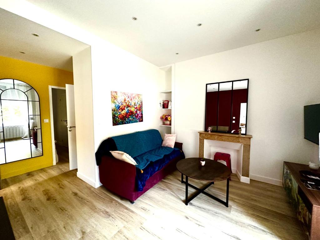 een woonkamer met een blauwe bank en een open haard bij Maison des Fleurs T2 superbes à 10 min de ST et Soitec in La Terrasse