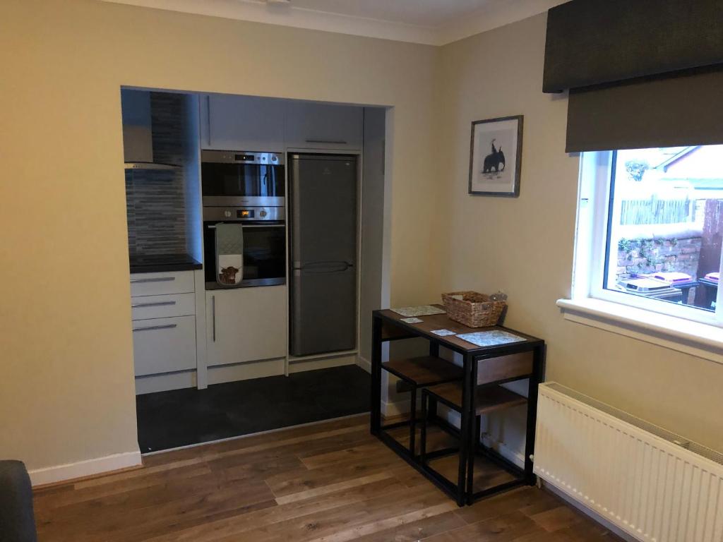 a kitchen with a refrigerator and a table and a window at Ideally Located Modern Flat in Troon