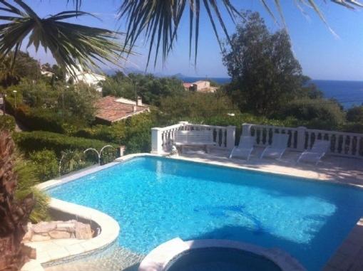 a swimming pool with chairs and the ocean in the background at Villa Manù B&B Chambre D'hote in Les Issambres