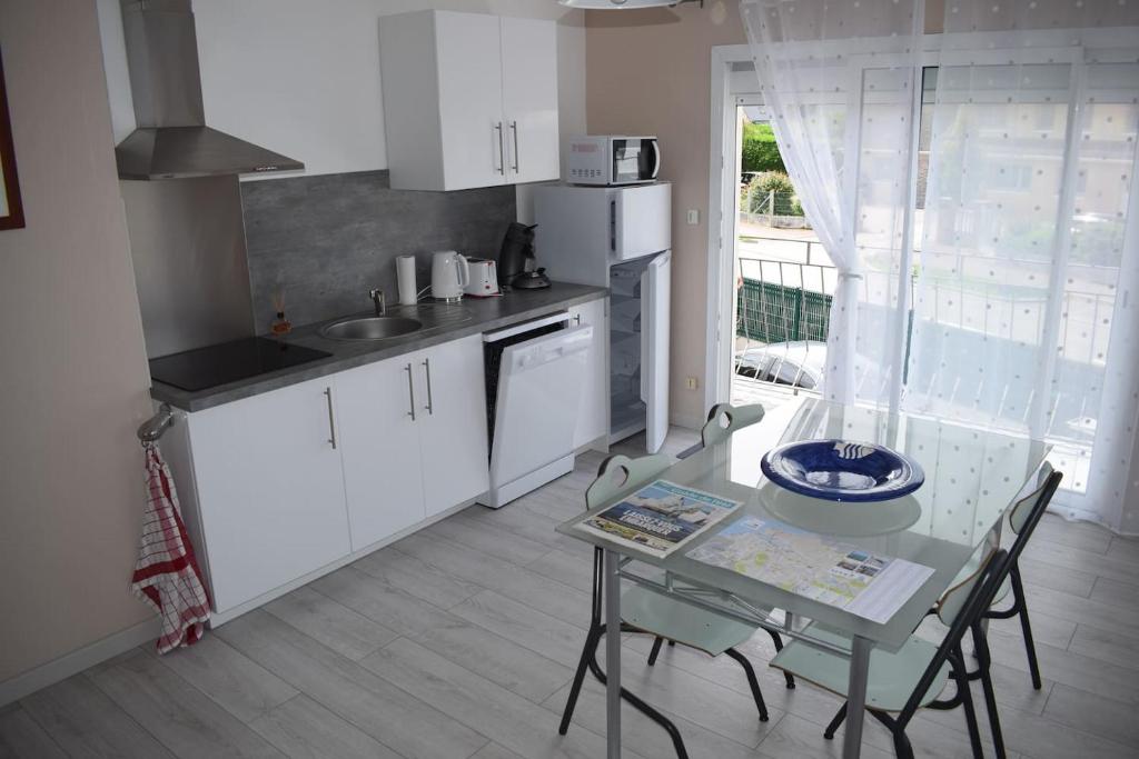 une cuisine avec des armoires blanches et une table avec des chaises dans l'établissement les hirondelles, à Fécamp