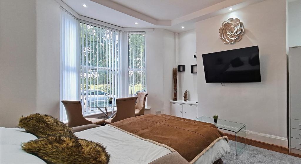 1 dormitorio con 1 cama y TV en la pared en Littlewood Gardens Escapes, Ideal Retreats with Green Views- Ideal Summer Stays en Liverpool