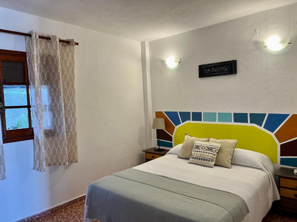 1 dormitorio con 1 cama con cabecero amarillo y ventana en Casa Los Palitos, en Monte de Breña