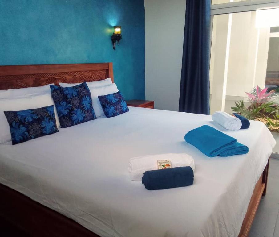 Una cama con toallas azules y blancas. en Matumaini Guest House, en Migogoni
