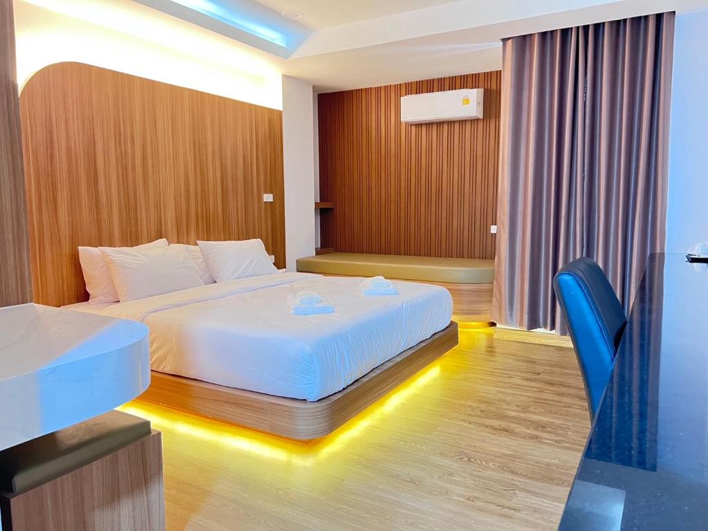 Cette chambre comprend un lit blanc et un bureau. dans l'établissement โรงแรม ชม เชียงราย, à Ban Hua Khwai (1)