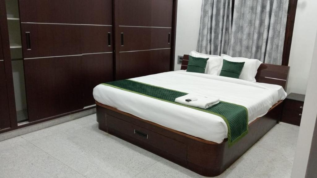 een slaapkamer met een groot bed met groene en witte kussens bij Atithi Homestay in Tirupati