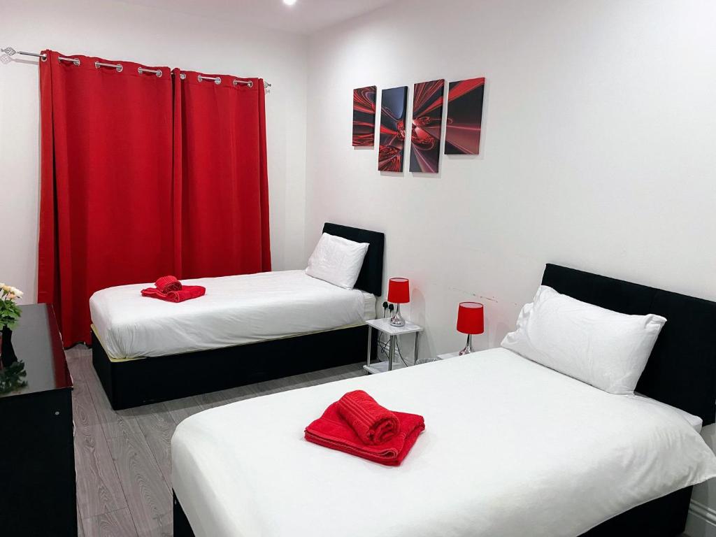 a room with two beds with red towels on them at Attractive 2 bed apartments free Wi-Fi and parking in Croydon