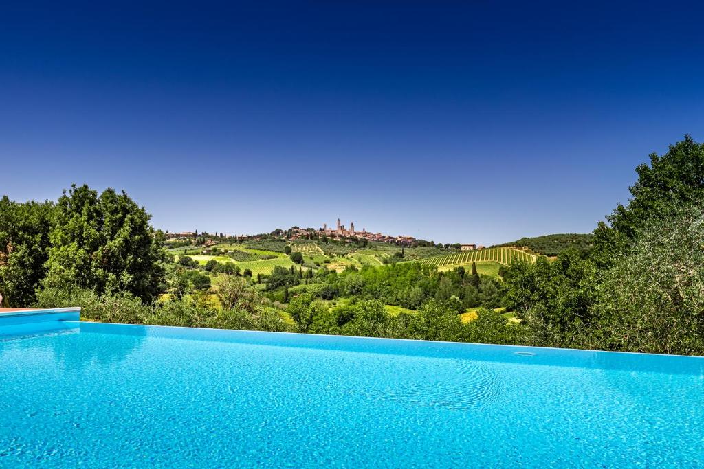 a blue swimming pool with a view of a hill at Agriturismo Poggiacolle in San Gimignano