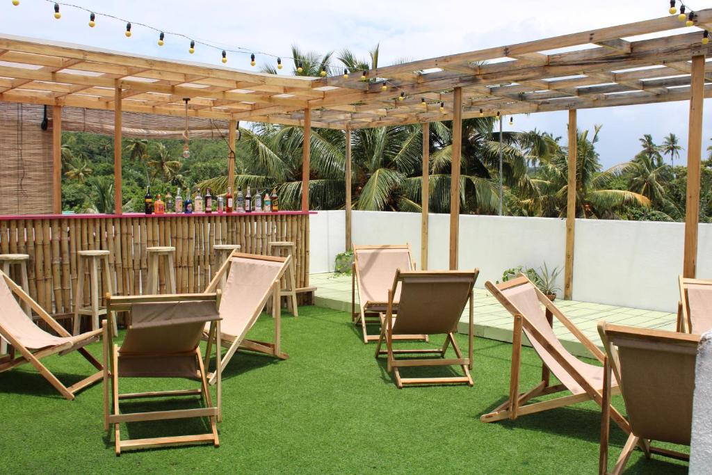 a group of chairs and tables under a pergola at Sun & Moon Hostel in Mirissa