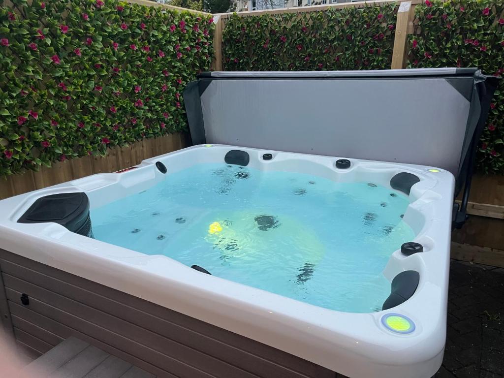 a jacuzzi tub in a backyard with flowers at St Annex, Boutique Holiday Apartment for 2 people in Torquay - with Private HOT TUB! in Torquay