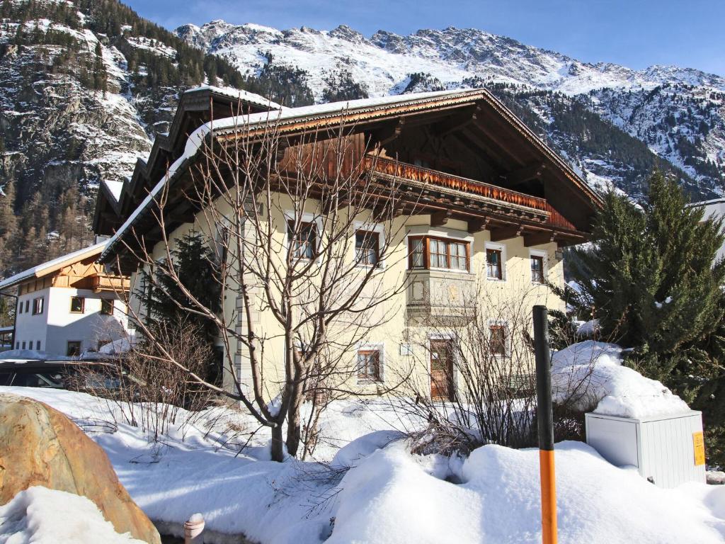 ein Haus im Schnee vor einem Berg in der Unterkunft Spacious Apartment in L ngenfeld with Sauna in Huben