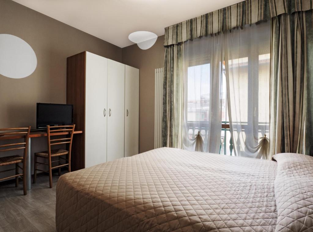 a bedroom with a bed and a desk and a window at Il Fiordaliso Foresteria in Busto Arsizio
