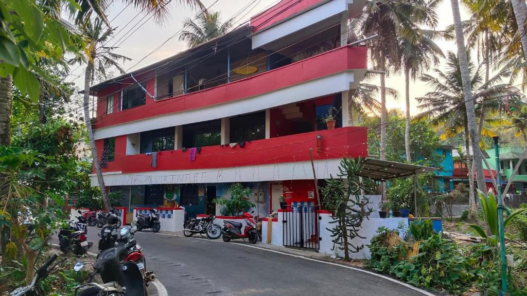 un edificio rojo con motocicletas estacionadas frente a él en Abhi's cafe avaduthura kovalam, en Kovalam