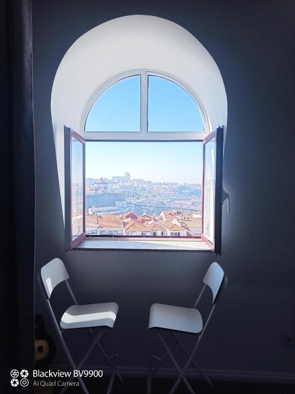 an arched window with two chairs in a room with a view at Oporto apartment Batalha in Porto