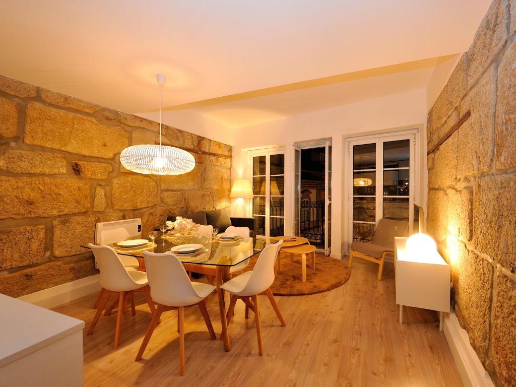 a dining room with a stone wall and a table and chairs at Largo São Domingos by Innapartments in Porto