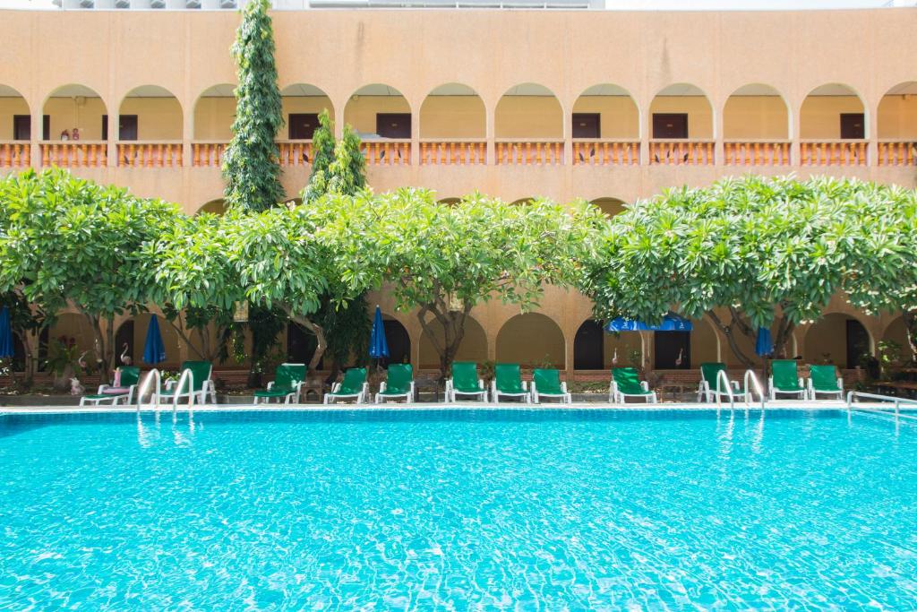 a large swimming pool with chairs and a building at S Lodge Pattaya formally Sabai Lodge in Pattaya