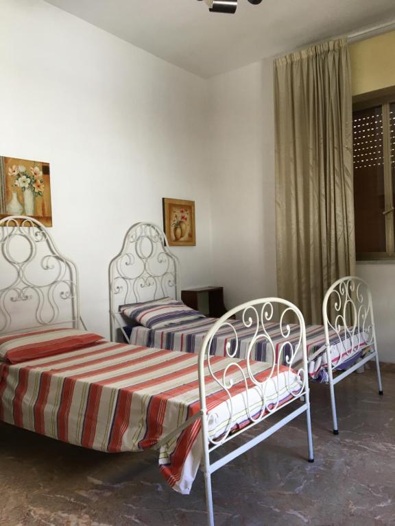 two beds sitting in a room with a window at Affittacamere al piano terra in Scicli