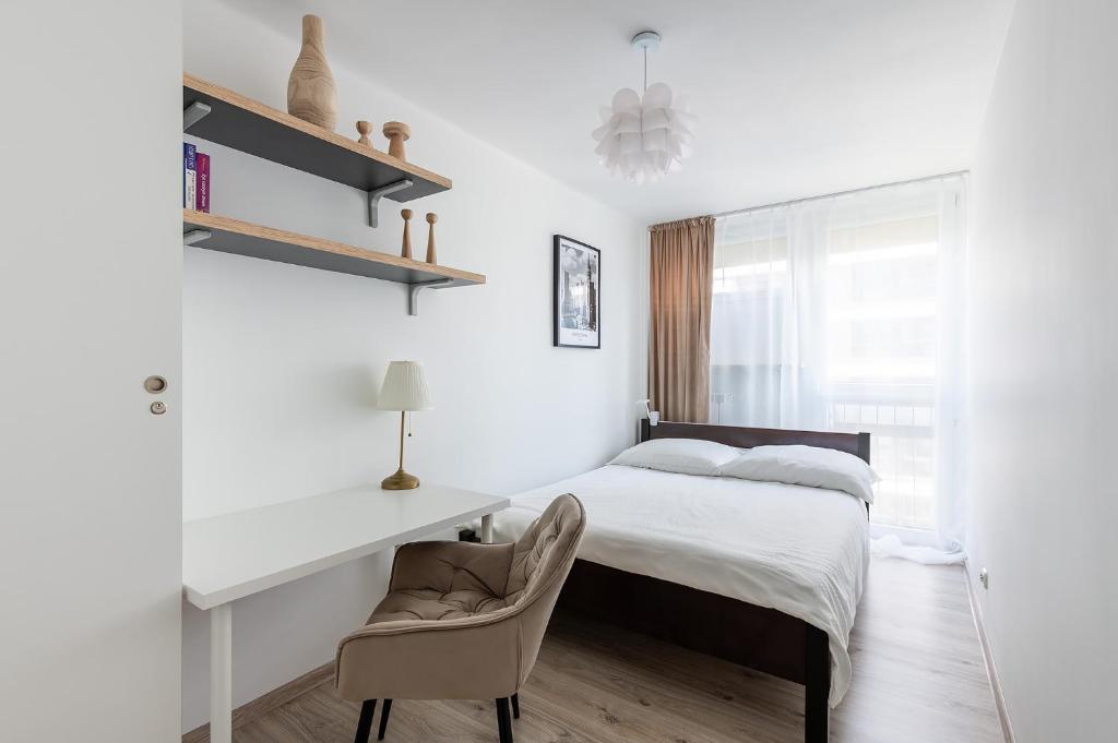 um quarto com uma cama, uma secretária e uma cadeira em Grzybowska39 Apartments em Varsóvia