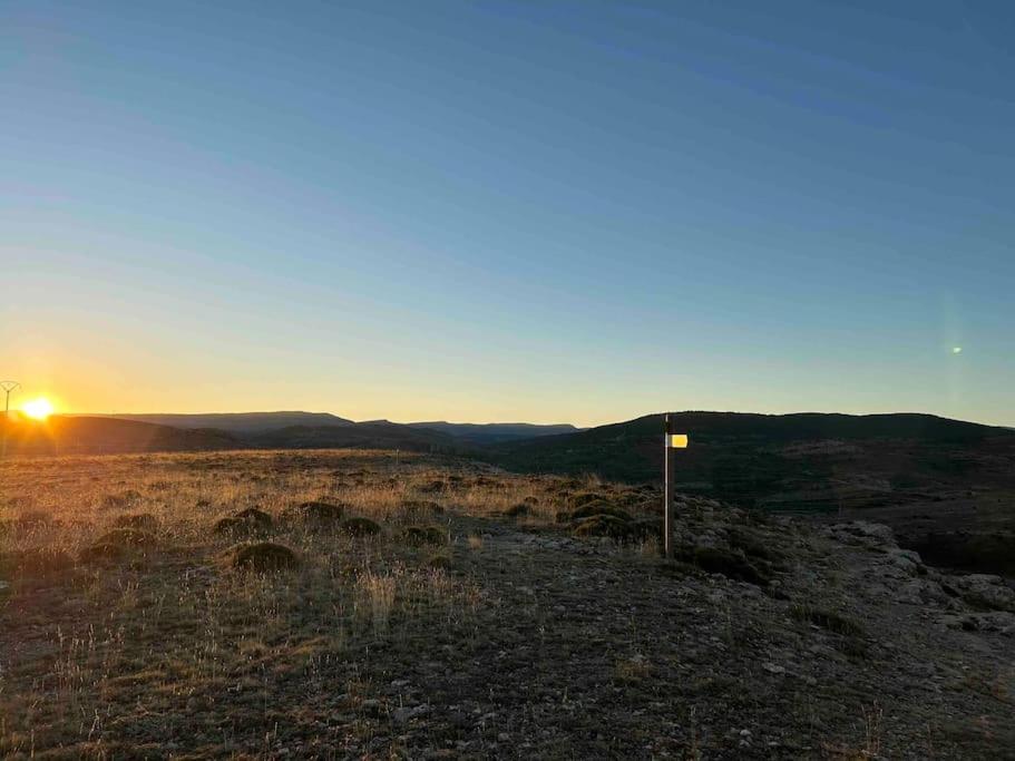 ein Sonnenuntergang auf einem Feld mit einem Schild auf einem Hügel in der Unterkunft Vistas Del Maestrazgo apartamentos Rurales in Allepuz