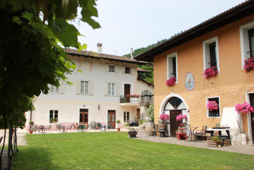 ein Gebäude mit einem Garten mit Stühlen und Tischen in der Unterkunft Agritur Cantina Romanese in Levico Terme